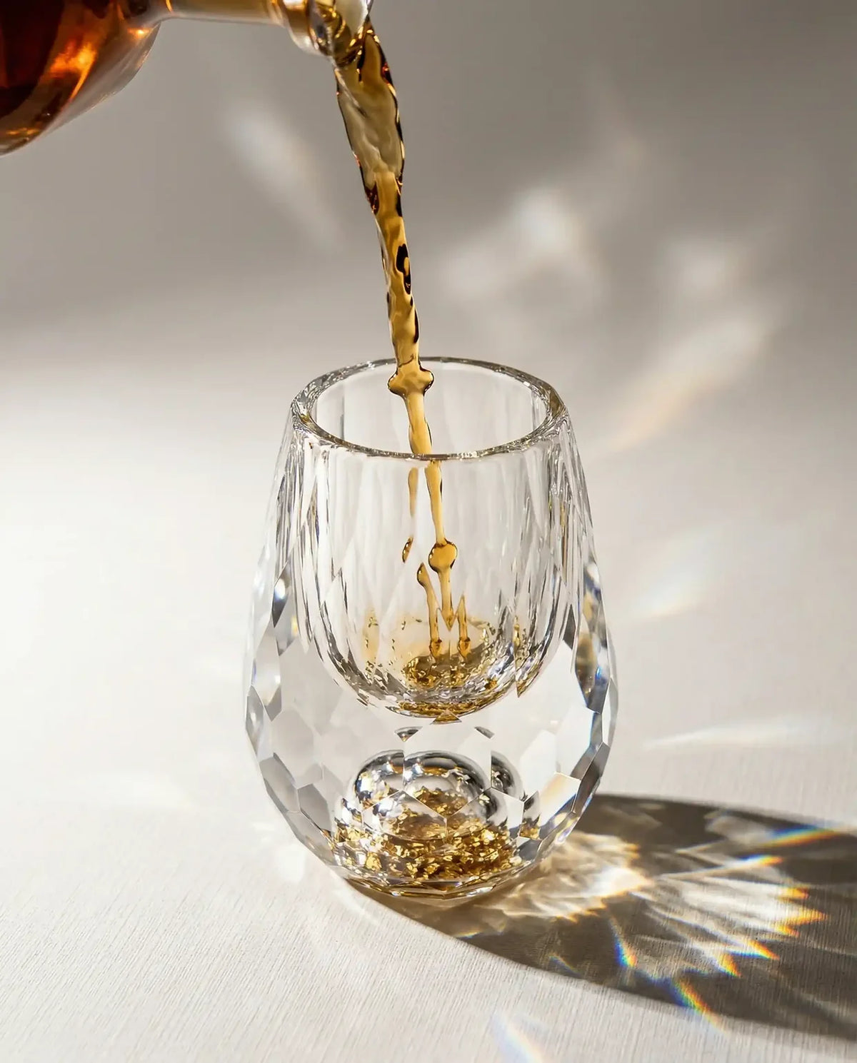 Whisky sendo servido no Cristallo, com reflexos de luz na mesa